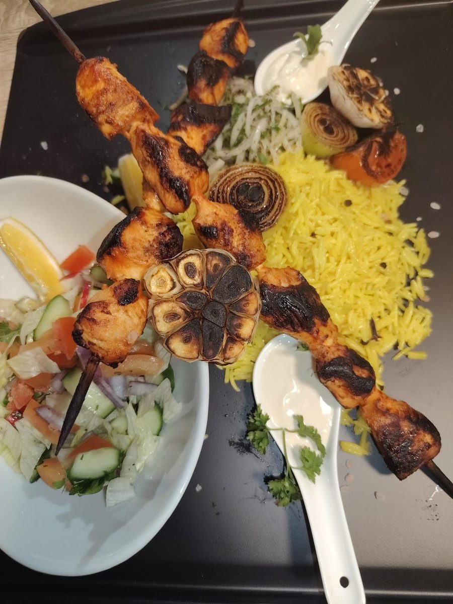 Two chicken shish taouk skewers with rice, garlic sauce and chopped salad